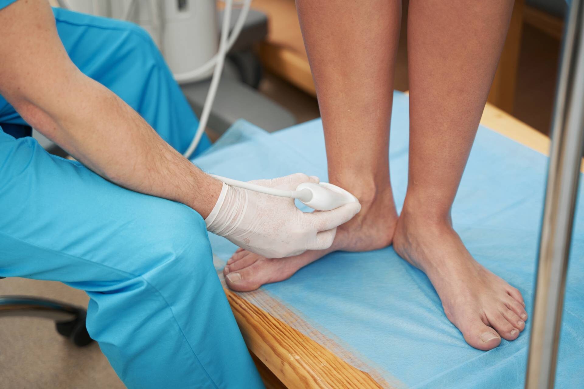 Caucasian doctor carefully examining female ankle joint with an ultrasound transducer