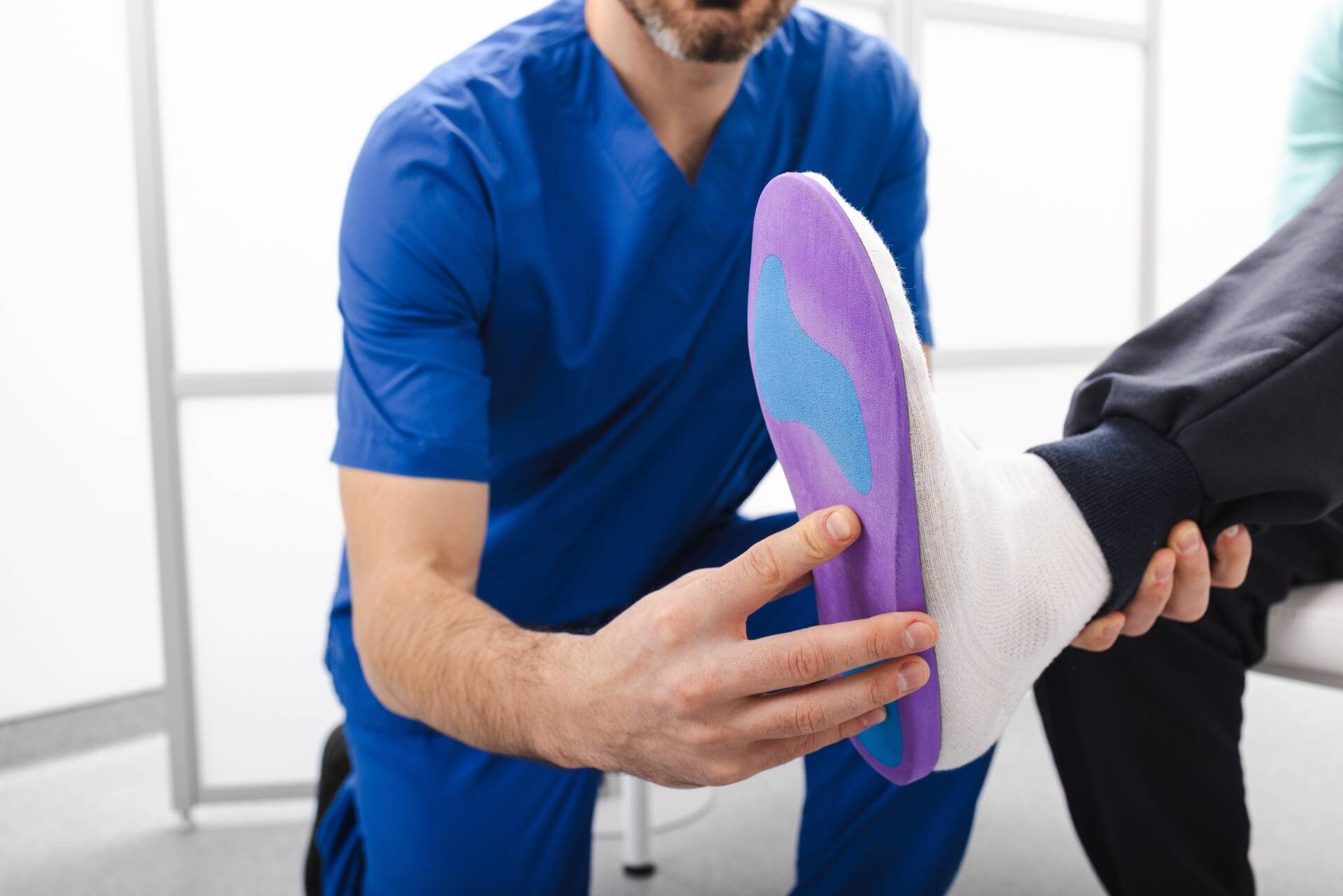 Orthopedist fitting individual orthopedic insole for patient foot. Orthopedic insoles
